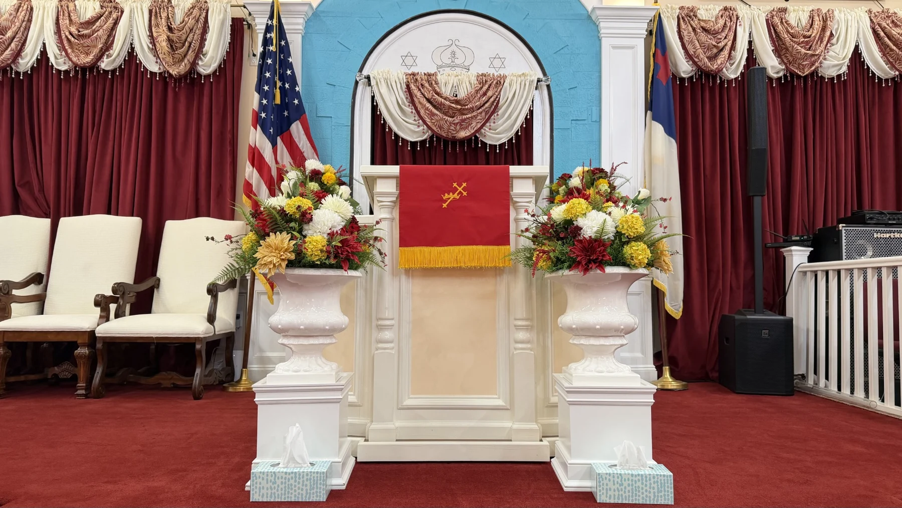 Altar de la Iglesia Cristiana Assael, con flores y cortinas color vino